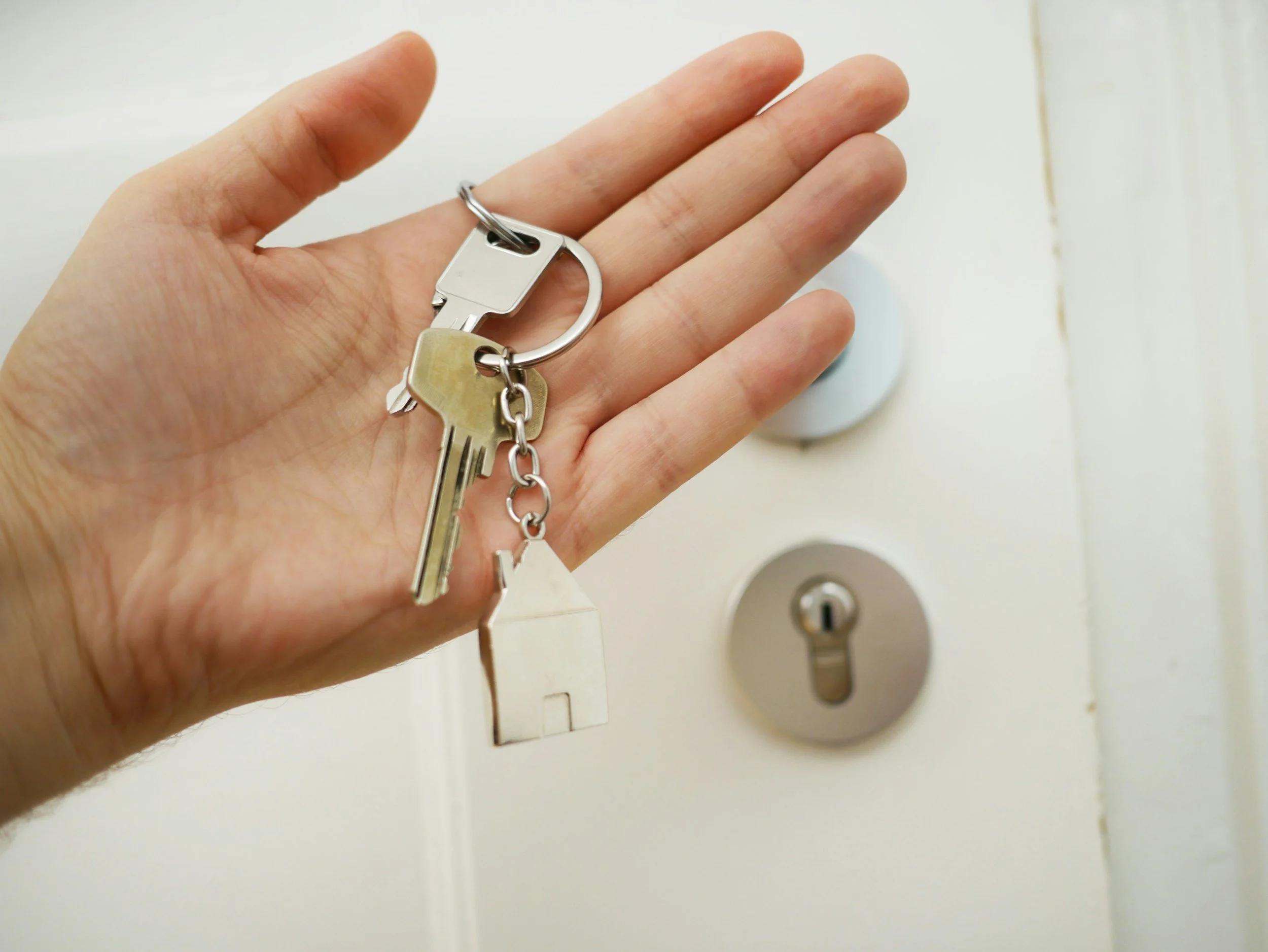 Hand holding keys in front of a door lock